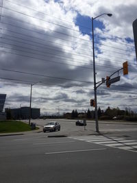 Road passing through city against cloudy sky