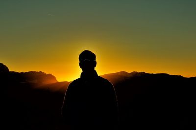 Silhouette man standing on mountain against sky during sunset