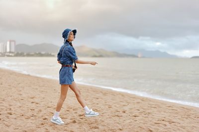 Full length of woman standing at beach against sky