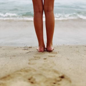 Low section of man standing on beach