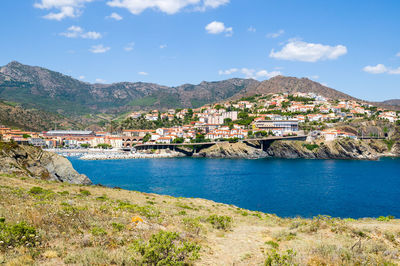 Scenic view of townscape by mountains against sky