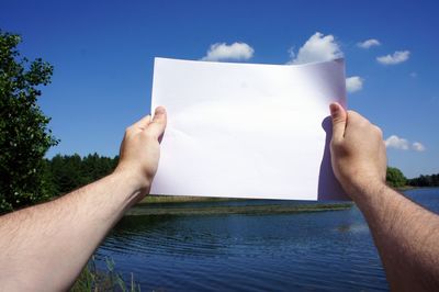 Midsection of man holding paper against sky