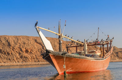 Fishing boat in sea against clear blue sky