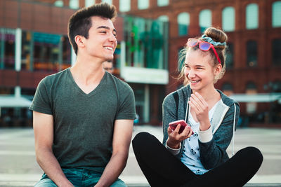 Young woman smiling while sitting in city