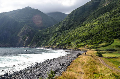 Scenic view of river by mountains against sky