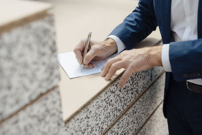 Hands of businessman writing on paper