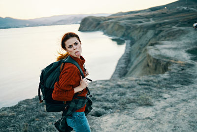 Portrait of young woman standing against waterfall