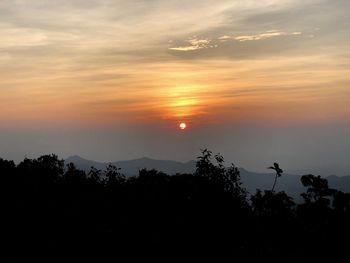 Scenic view of silhouette mountains against orange sky