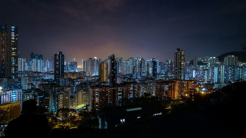 Illuminated buildings in city against sky at night