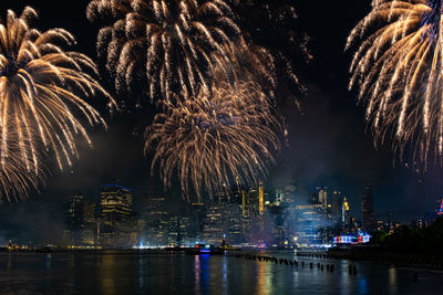 Firework display over river by buildings at night