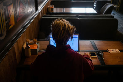 Rear view of woman sitting on table