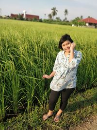 Full length of smiling young woman standing in field