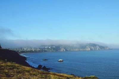 Scenic view of sea and mountains against clear blue sky