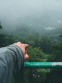 Cropped hand touching railing on mountain