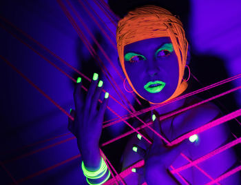 Portrait of young woman against illuminated wall