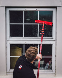 Rear view of man standing by window of building