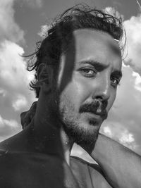 Close-up portrait of young man against sky