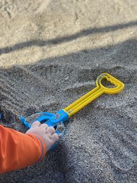 High angle view of hand holding yellow umbrella on beach