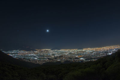 Illuminated cityscape against sky at night