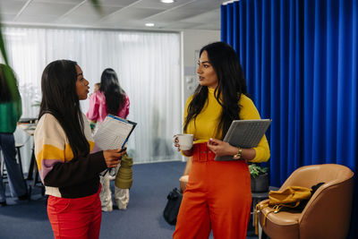 Female business professionals discussing while standing at office