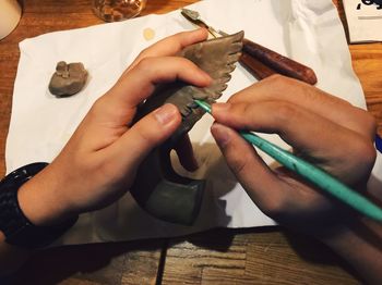 Close-up of hands carving on clay