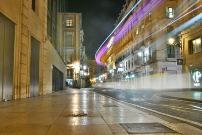 Illuminated street amidst buildings in city at night