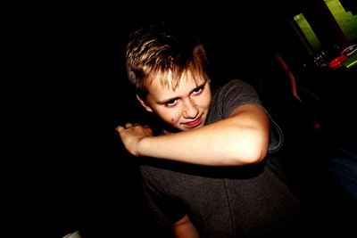 Tilt shot of teenage boy doing dab dance in dark