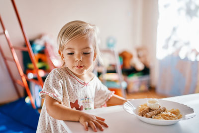 Portrait of cute girl eating food at home