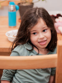 Cute little girl making faces for the camera while sitting at a table