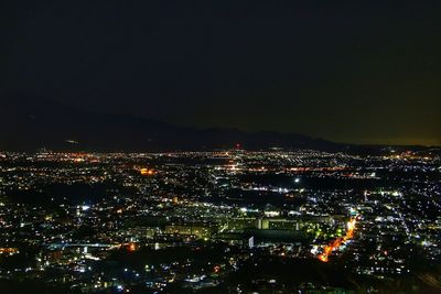 Illuminated cityscape against sky at night