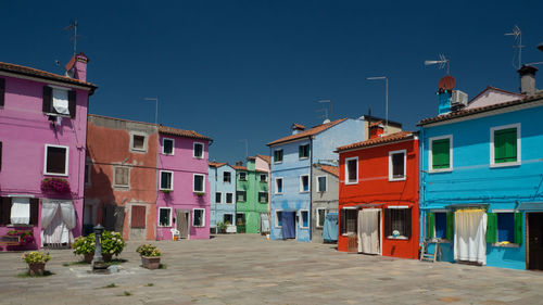 Street amidst buildings against blue sky