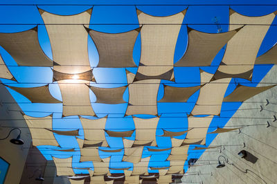 Low angle view of umbrellas hanging against blue sky