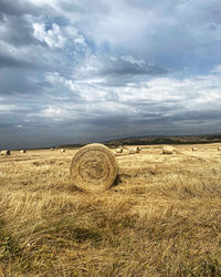 Hay bales on field against sky