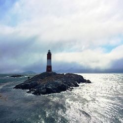 Lighthouse by sea against sky