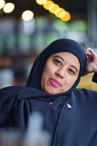 Portrait of indonesian muslim woman wearing black hijab with bokeh.