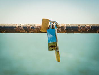 Close-up of padlocks hanging on metal against sky