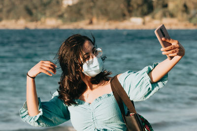 Woman photographing with mobile phone in sea