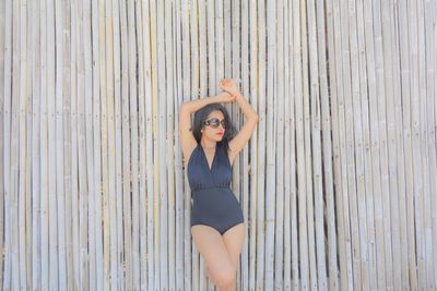 Woman in swimsuit standing by bamboos