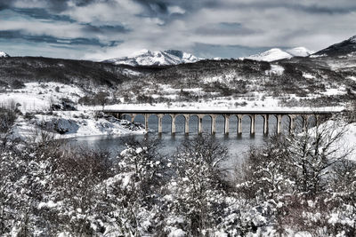 Bridge over snowcapped mountains against sky