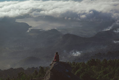 Man standing on rock against sky