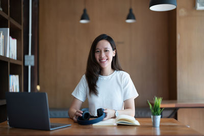 Portrait of young woman sitting on table