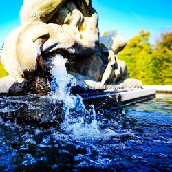 Close-up of water splashing on riverbank against blue sky