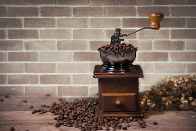 Coffee grinder with beans on table against wall