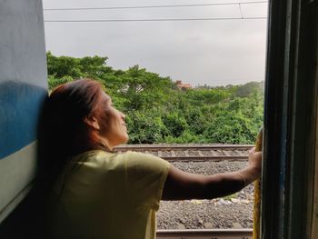 Rear view of woman looking through window