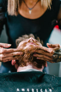 Close-up of woman shaving man beard