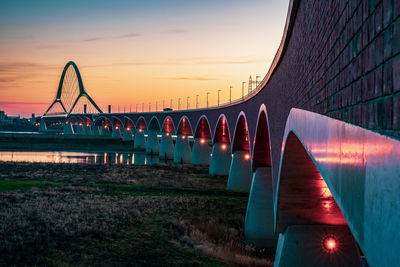 The de oversteek bridge in the dutch city of nijmegen is illuminated in the evening.