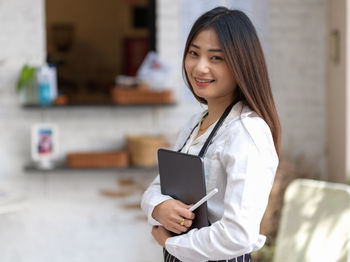 Portrait of young businesswoman holding digital tablet at office