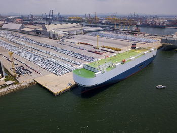 Aerial logistics commercial vehicles waiting to be load on to a car carrier ship at dockyard