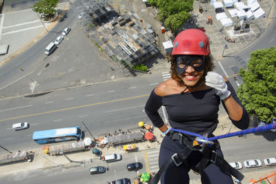 A woman wearing a hero costume with protective helmet walking down a tall rappel building. 