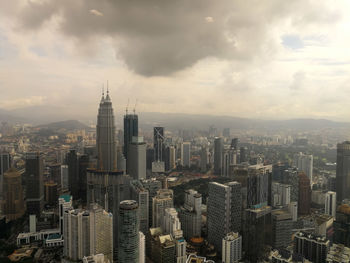 Aerial view of buildings in city against cloudy sky